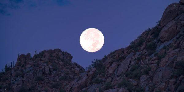 Full moon setting over Granite Mountain near Scottsdale, Arizona, with saguaro cacti at dawn