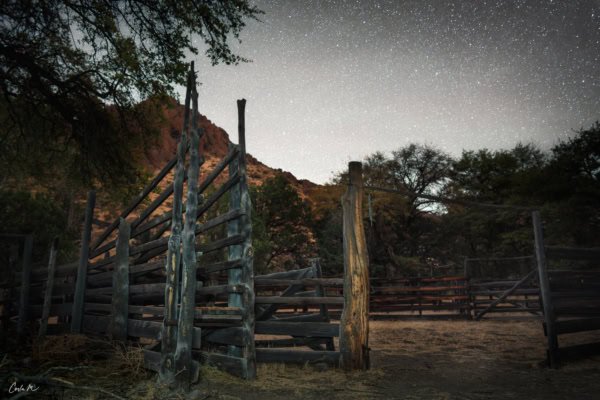 Historic cattle corral with cedar posts under a starry night sky in Arizona's Chiricahua National Monument.