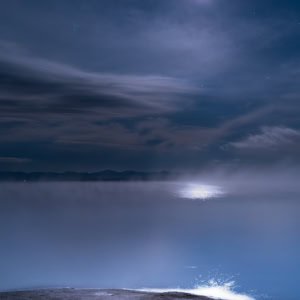 Yellowstone National Park nightscape with Fishing Cone geyser steaming under moonlight.