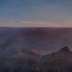 Grand Canyon panoramic photograph with wildfire smoke and a blazing red moon over the hazy beauty of the canyon.