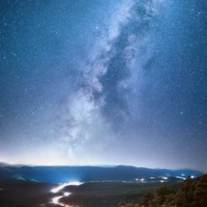 Car light trails creating a river of light on a winding road under the Milky Way in Arizona.