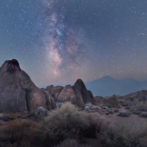 Night sky photograph of the Milky Way and stars shining through forest fire smoke in Alabama Hills, California.