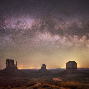 Milky Way arch over Monument Valley's mittens buttes in the Arizona-Utah desert.