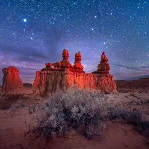 A panoramic night photograph of a rock formation under a starry sky at Goblin Valley State Park, Utah.