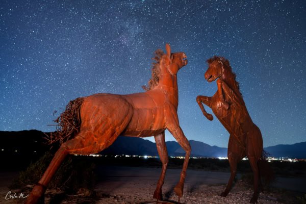 A night photograph of two metal horse sculptures fighting under a starry sky in the Anza-Borrego Desert.