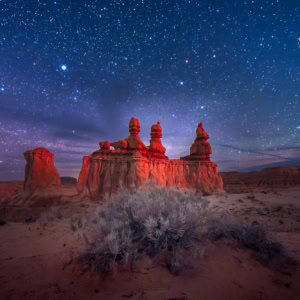A panoramic night photograph of a rock formation under a starry sky at Goblin Valley State Park, Utah.