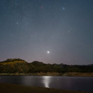Night sky landscape photograph of Venus reflecting on Bartlett Lake in Arizona.